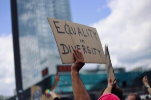 Cardboard sign with the words equality in diversity written in black pen
